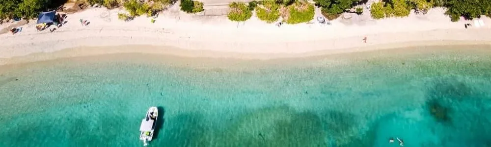 Aerial view of a small boat moored in clear shallow water off a Far North Queensland beach